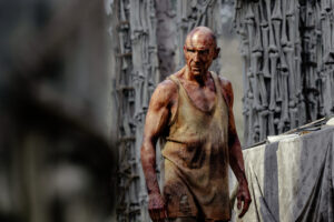Ralph Fiennes frente a una columna de huesos.